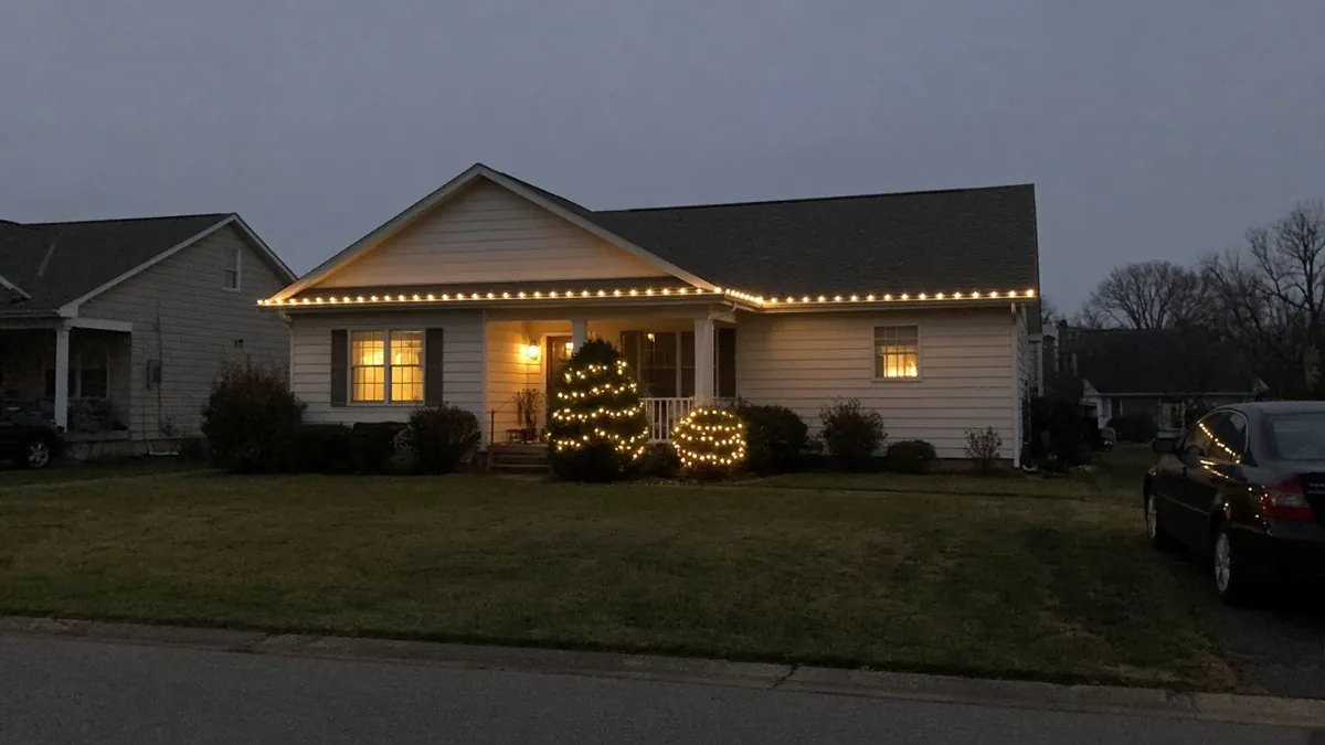 House at dusk with warm white holiday lights along the roofline